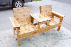 two wooden chairs sitting next to each other near a car parked on the side walk