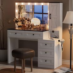 a white vanity with lights on it next to a chair and table in front of a window