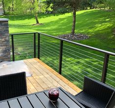 a glass of wine sitting on top of a wooden table next to a black chair