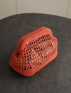 an orange crocheted purse sitting on top of a black table next to a white wall