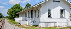 a small white train station sitting on the tracks