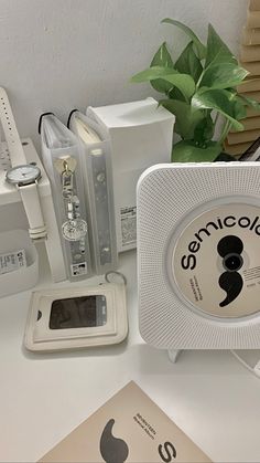 an electronic device sitting on top of a table next to a plant and other electronics