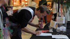 a man writing on a piece of paper at a table