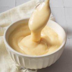 a spoon in a bowl filled with mayonnaise on top of a table cloth