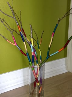 there is a vase that has some branches in it and colorful crayons sticking out of the stems