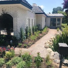 a white brick house surrounded by flowers and trees