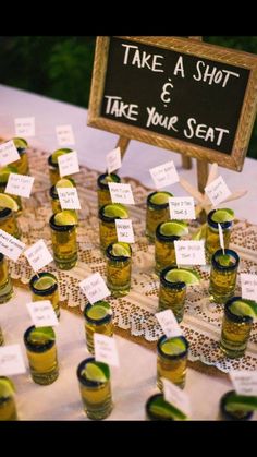 there are many shot glasses with limes in them sitting on the table next to each other