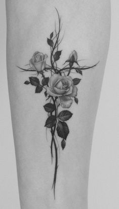 a black and white photo of a cross with roses on it's side thigh