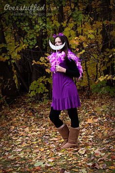 a woman in a purple dress is posing for the camera with her hands on her hips