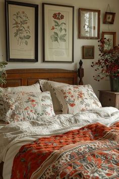 a bed with two pictures above it and flowers in vases on the wall behind it