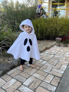 a young child dressed in a costume standing on a brick walkway with plants and bushes behind them