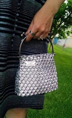 a woman holding a purse in her hand on the grass with trees in the background