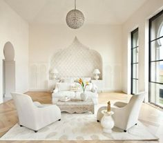 a living room with white furniture and large windows