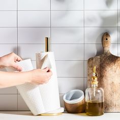 a person is holding two rolls of toilet paper in front of the bathroom sink and soap dispenser