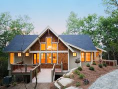 a house that is in the woods with lots of lights on it's windows