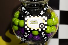 a glass jar filled with green and black candies on top of a checkered wall