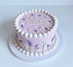 a pink birthday cake with white frosting and purple flowers