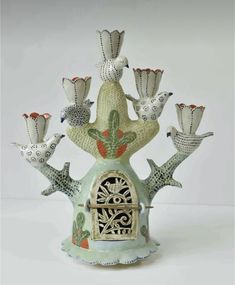 a ceramic bird house with nine birds perched on it's roof