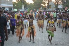 some people are walking down the street with costumes and headdress on their heads