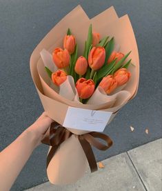 a person holding a bouquet of orange tulips