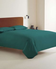 a bed with green sheets and pillows in a room