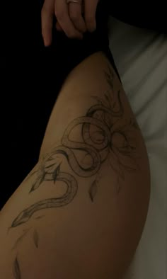 a woman's thigh with tattoos on it and her hand resting on the leg