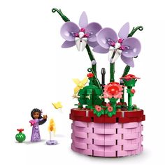 a flower pot with flowers in it next to a lego figure and toy figurine