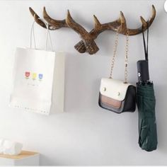 two purses hanging on the wall with deer horns attached to it's hooks