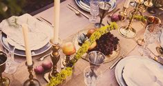 the table is set with plates, silverware and fruit