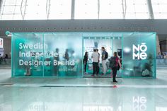 people standing in front of an advertisement for swedish independent designer brand no me at the airport