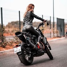 a woman in black leather riding on the back of a motorcycle