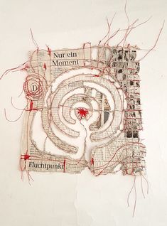 a piece of paper with red thread on it and an image of a spiral in the middle