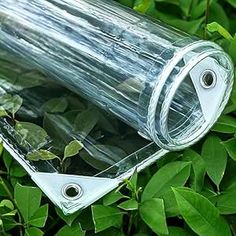 a clear plastic object laying on top of some green leaves in the grass and bushes