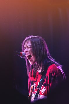 a woman with long hair singing into a microphone