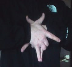 a person with their hands in the shape of two fingers pointing at something while wearing a black shirt