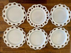 six white plates sitting on top of a wooden table