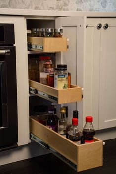 an open cabinet with spices, condiments and other items in the bottom drawer