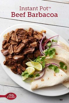 a white plate topped with meat and veggies next to tortilla bread