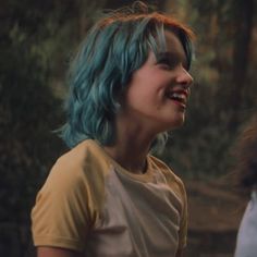 a woman with blue hair is smiling at something