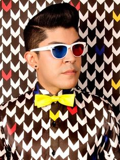 a young man wearing sunglasses and a bow tie with an unusual pattern on the background