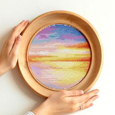 a person is holding up a cross - stitch pattern in front of a white wall