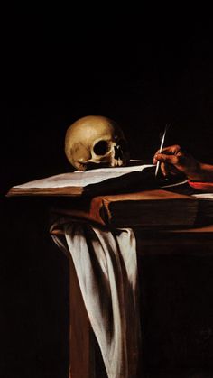 a painting of a human skull sitting at a table with an open book and pen