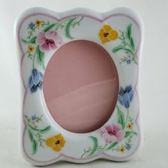 a white and pink plate with flowers on the border is sitting on a table top