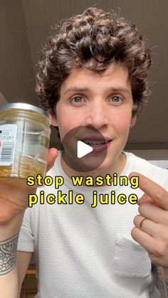 a young man holding a jar of picklejuice in front of his face