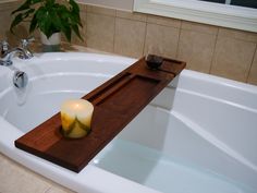 a candle sitting on top of a wooden tray in a bathtub next to a window