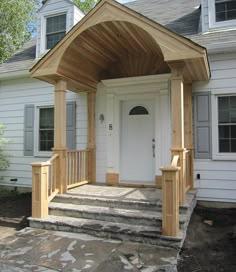 a white house with a wooden porch and steps leading up to the front door area