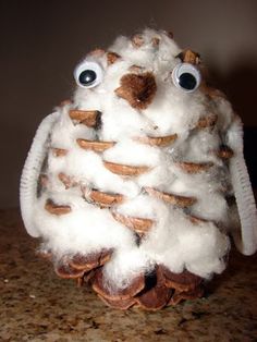 a close up of a stuffed animal made out of cotton balls and pinecones