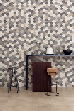 two stools and a table in front of a wall with hexagonal tiles