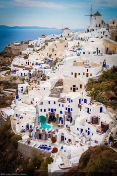 an aerial view of white buildings with blue shutters on the roof and water in the background