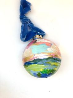 a glass ornament with a blue ribbon hanging from it's side on a white surface